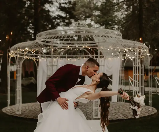 Grafika Romantyczny pocałunek młodej pary przed elegancką altaną ogrodową.