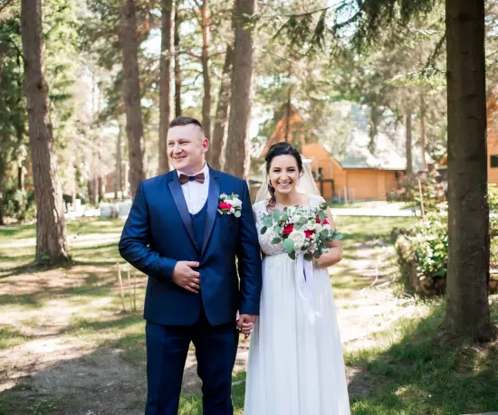 Grafika Młoda para w strojach ślubnych wśród drzew.
